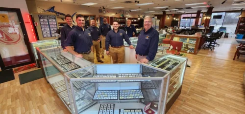 A photo of the Fox Valley owner and employees in front of coins in a countertop
